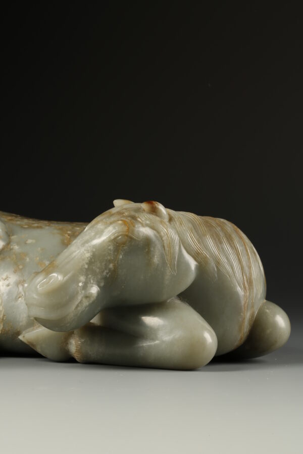 A celadon jade reclining horse with brown mottling (Late Ming dynasty, 17th century)