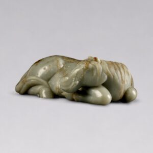 A celadon jade reclining horse with brown mottling (Late Ming dynasty, 17th century)